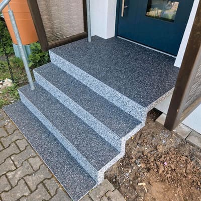 Sanierte Eingangstreppe mit anthrazitfarbenem Steinteppich vor einer blauen Haustür – Treppensanierung außen von mf.steintechnik aus Kirchheim am Neckar